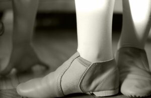 Close-up of tan slip-on jazz shoes worn with tights